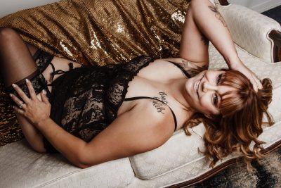 Boudoir photograph of woman in black lingerie with gold sequins.