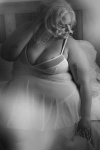 Boudoir photo of woman in white lingerie sitting on a bed.  southern Wisconsin