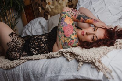 Women laying on a bed wearing forest green lingerie at her boudoir session in Wisconsin