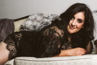 Woman in black lingerie laying on vintage couch in Madison, WI for her boudoir photography session