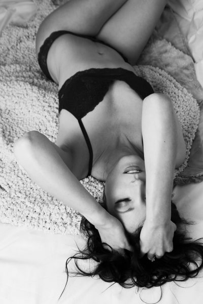 Black and white photo of woman laying on her back in black lingerie in Wisconsin
