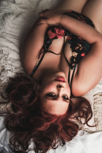 Beautiful boudoir photo of chestnut hair woman laying on bed with floral lingerie